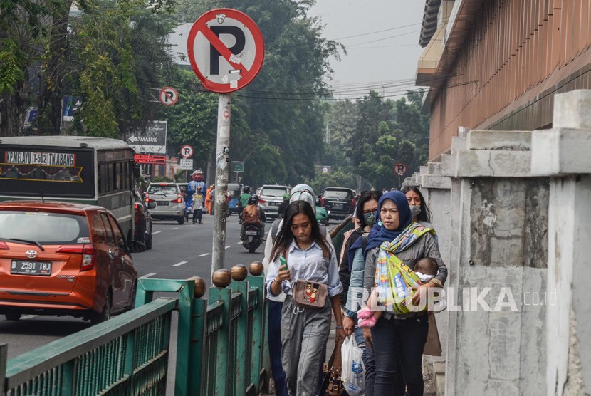 Pejalan kaki melintasi trotoar di daerah Stasiun Cikini, Jakarta Pusat. Pejalan kaki menjadi kelompok paling rentan yang terdampak polusi udara.