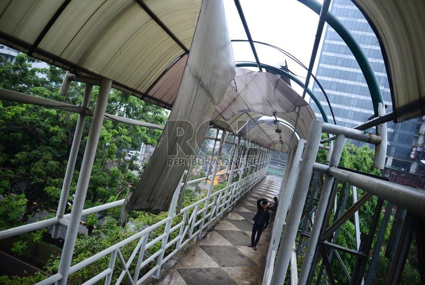 Pejalan kaki melintasi Jembatan Penyeberangan Orang (JPO) dengan atapnya yang rusak di Jalan Rasuda Said, Jakarta Selatan, Senin (12/1).(Republika/Raisan Al Farisi)