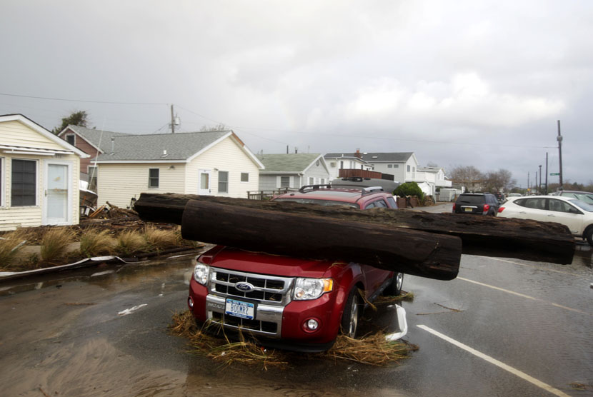 Reruntuhan sebatang pohon besar menimpa sebuah mobil di Breezy Point New York, Selasa (30/10). (Frank Franklin II/AP)