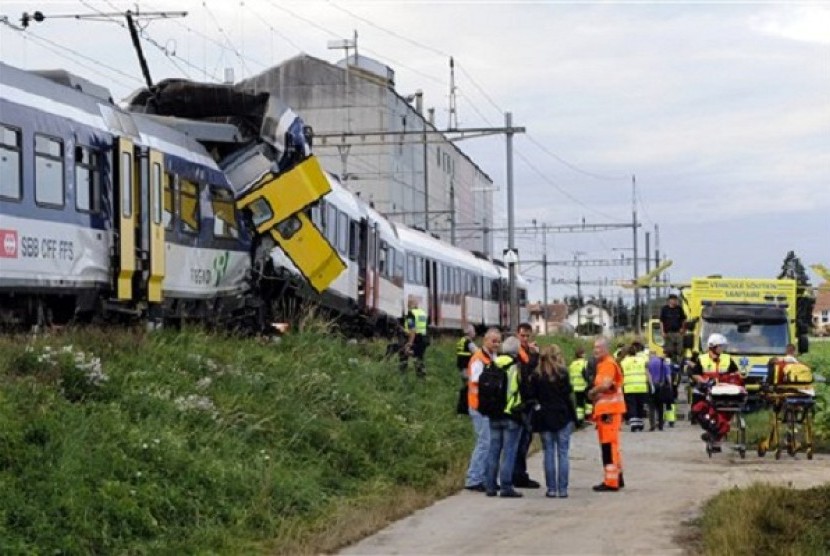 Rescue personnel work at the site where two passenger trains collided head-on in Granges-pres-Marnand, western Switzerland, Monday, July 29, 2013. Police say at least 44 people were injured, four of them seriously. 