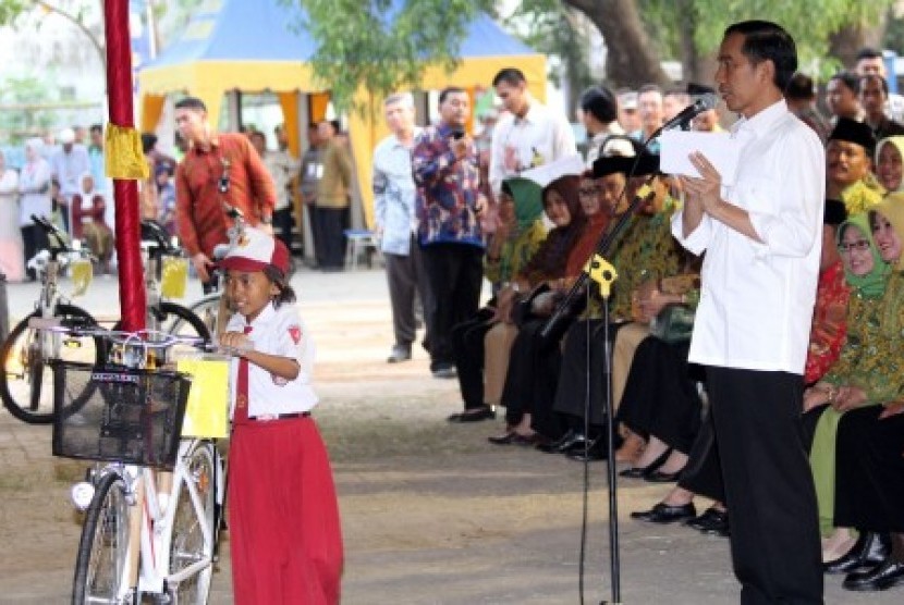 residen Joko Widodo (kanan) membagikan sepeda pada pelajar disela-sela penyerahan Kartu Keluarga Sejahtera (KKS), Kartu Indonesia Sehat (KIS) dan Kartu Indonesia Pintar (KIP) di STIKES ICMI Desa Kaliwungu Jombang, Jawa Timur, Sabtu (1/8). 