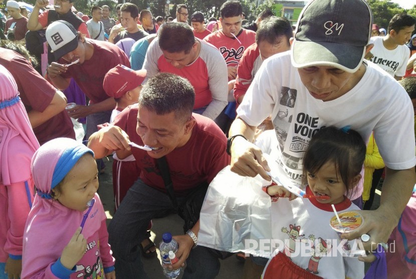 Ribuan pasangan ayah dan anak di Kota Sukabumi melakukan gosok gigi massal di Lapangan Merdeka, Kota Sukabumi, Ahad (12/3). Kegiatan tersebut digelar dalam rangka meningkatkan pemahaman anak dan orangtua mengenai pentingnya memelihara kesehatan gigi.