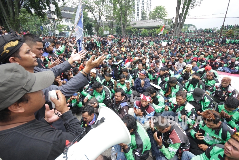 Ribuan pengemudi trasportasi berbasisi aplikasi online berdoa saat menggelar aksi di depan Gedung Sate, Kota Bandung, Senin (16/10).