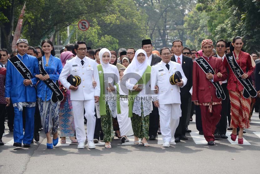   Ridwan Kamil (kiri) dan Oden M Danial (kanan) beserta istri berjalan kaki dari hotel menuju Gedung DPRD Kota Bandung untuk mengikuti upacara pelantikan Wali Kota dan Wakil Wali Kota Bandung, Senin (16/9).    (Republika/Edi Yusuf)