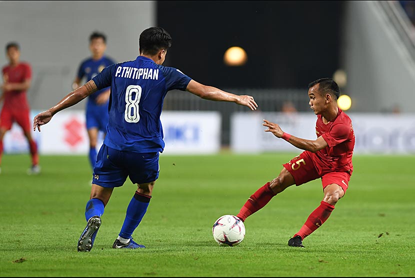 Riko Simanjuntak (kanan) menggocek bola dari sergapan bek Thailand Thitiphan Puangjan (kiri) dalam laga lanjutan Piala AFF 2018 di Stadion Nasional Rajamangala, Bangkok, Thailand, Sabtu (17/11)