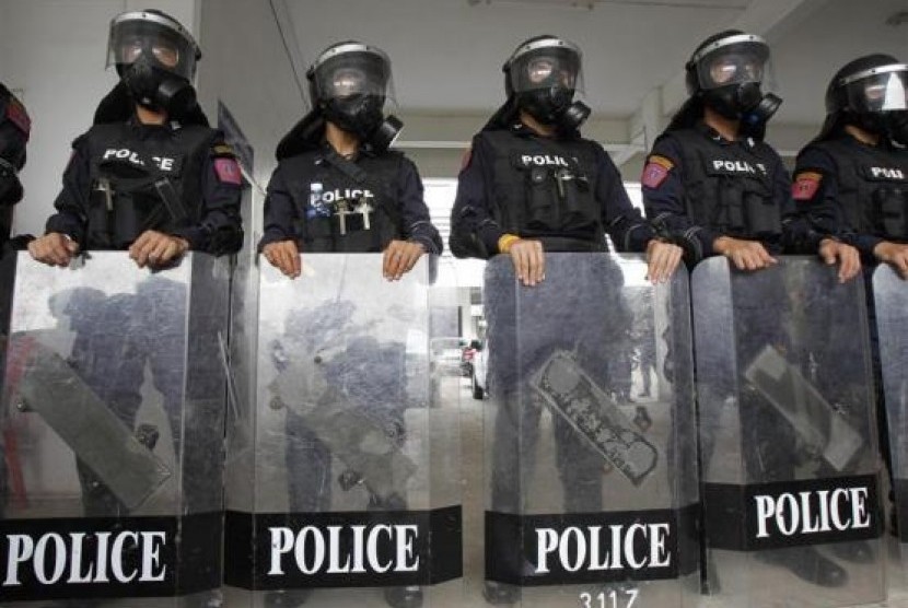 Riot police officers, wearing gas masks, stand with their shields during a demonstration for the media at the Royal Thai Police Sport Club in Bangkok January 7, 2014.