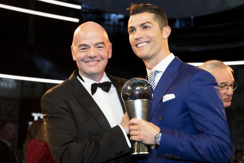 Cristiano Ronaldo (kanan) memegang trofi pemain terbaik 2016 versi FIFA berfoto bersama Presiden FIFA Gianni Infantino, Senin (9/1).