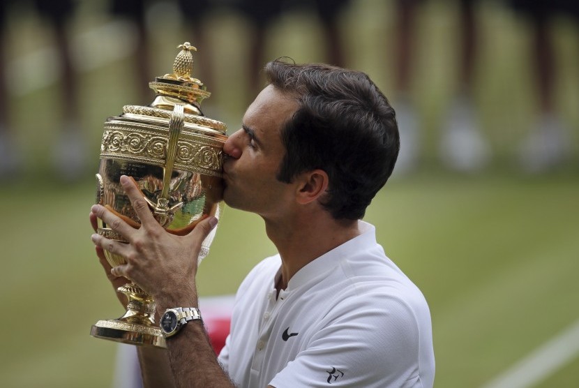 Roger Federer mencium trofi Wimbledon setelah mengalahkan Marin Cilic pada partai final, Ahad (16/7).