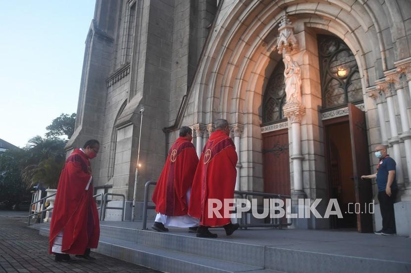 Romo Albertus Hani Rudi Hartoko (kiri) memasuki gereja untuk memimpin ibadat Jumat Agung di Gereja Katedral, Jakarta, Jumat (2/4/2021). 