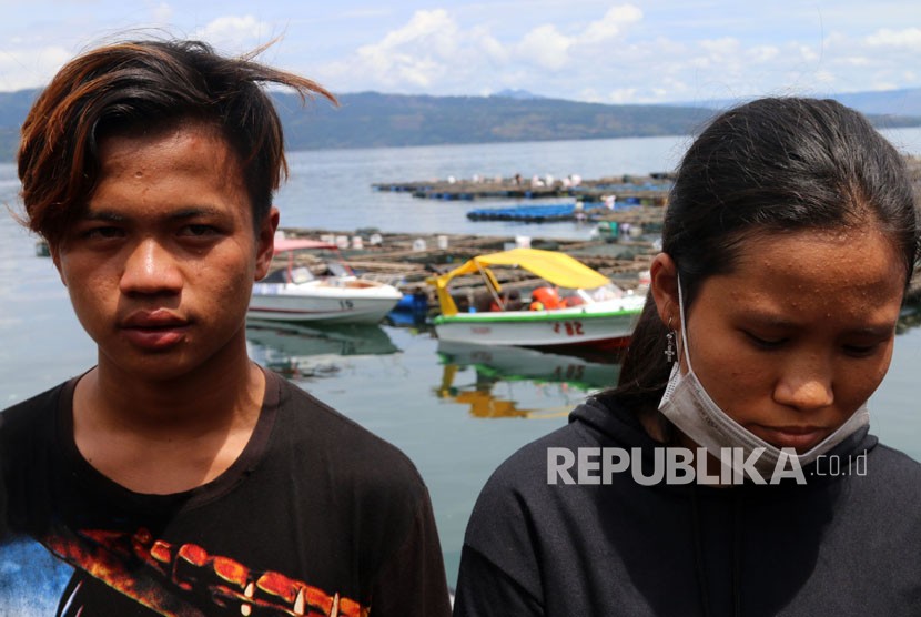 Roni Siadari (kiri) dan Tiambun Syahnia (kanan) dua penumpang KM Sinar Bangun yang selamat, berdiri di kawasan dermaga Tigaras, Danau Toba, di Simalungun, Sumatera Utara, Ahad (24/6).