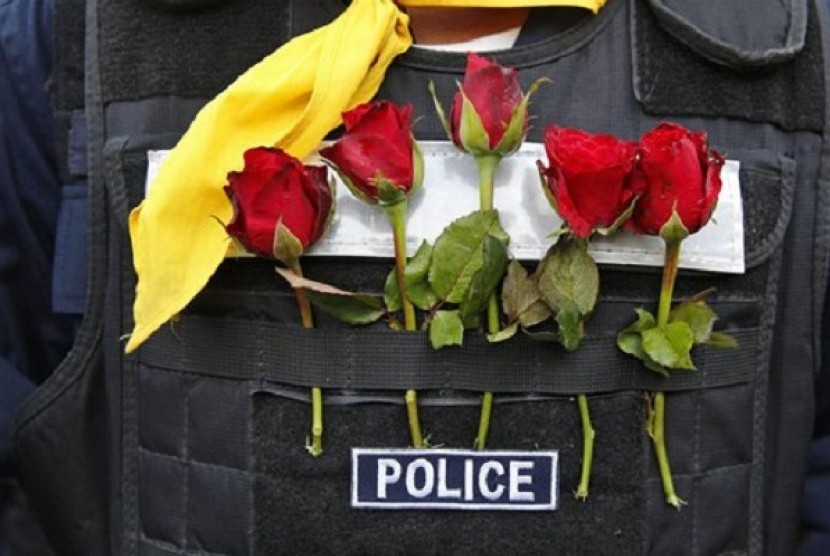 Roses offered by anti-government protesters decorate a Thai policeman's bulletproof vest outside city police headquarters, in Bangkok, Thailand Tuesday, Dec. 3, 2013. 