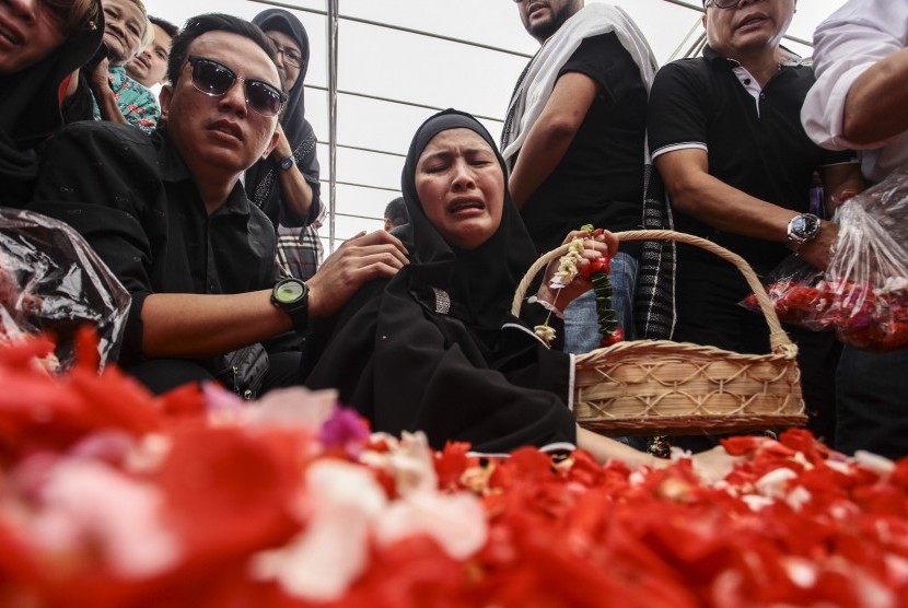 Almyanda Safira (tengah) ibunda dari korban tewas dalam kasus pembunuhan Pulomas Dianita Gemma Dzalfayla dan Diona Arika Andra Putri menaburkan bunga di makam kedua anaknya di TPU Tanah Kusir, Jakarta, Rabu (28/12).