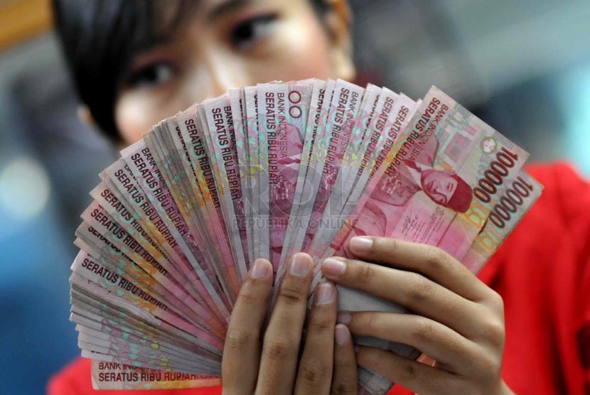 Petugas menghitung uang kertas Rupiah di jasa penukaran valuta asing, Jakarta.