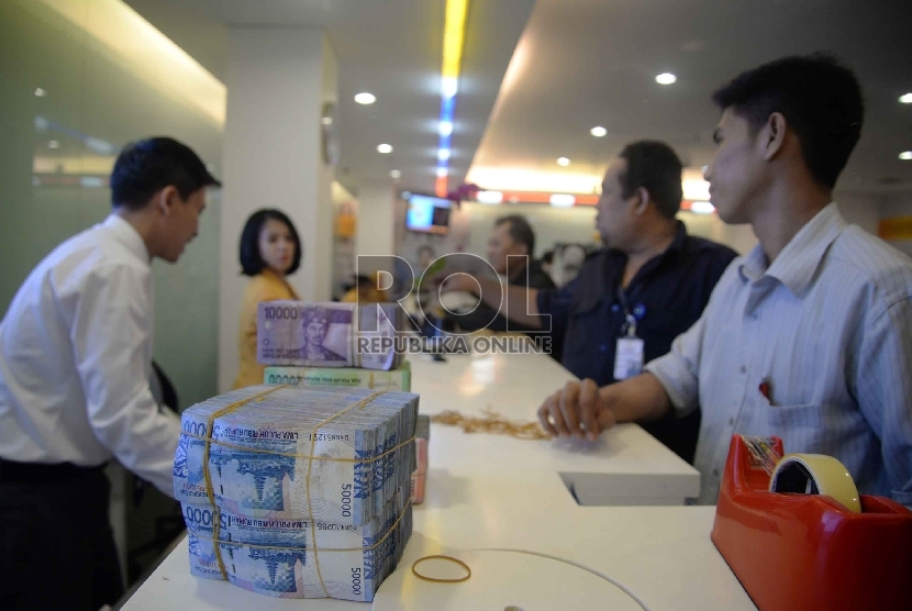 Rupiah Semakin Melemah: Teller melakukan transaksi dengan nasabah di Banking Hall Bank Mandiri, Jakarta, Rabu (11/3). 