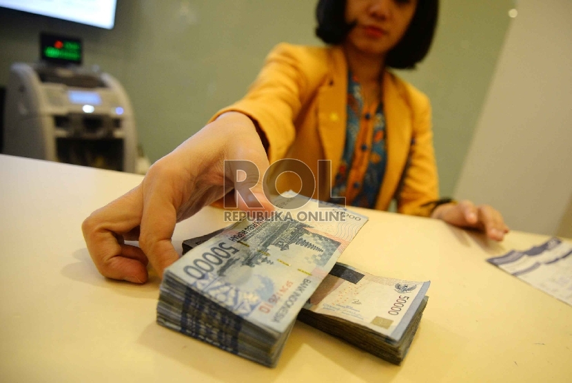 Rupiah Semakin Melemah: Teller melakukan transaksi dengan nasabah di Banking Hall Bank Mandiri, Jakarta, Rabu (11/3).