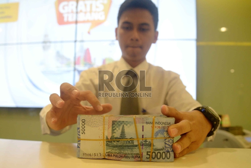 Rupiah Semakin Melemah: Teller melakukan transaksi dengan nasabah di Banking Hall Bank Mandiri, Jakarta, Rabu (11/3).