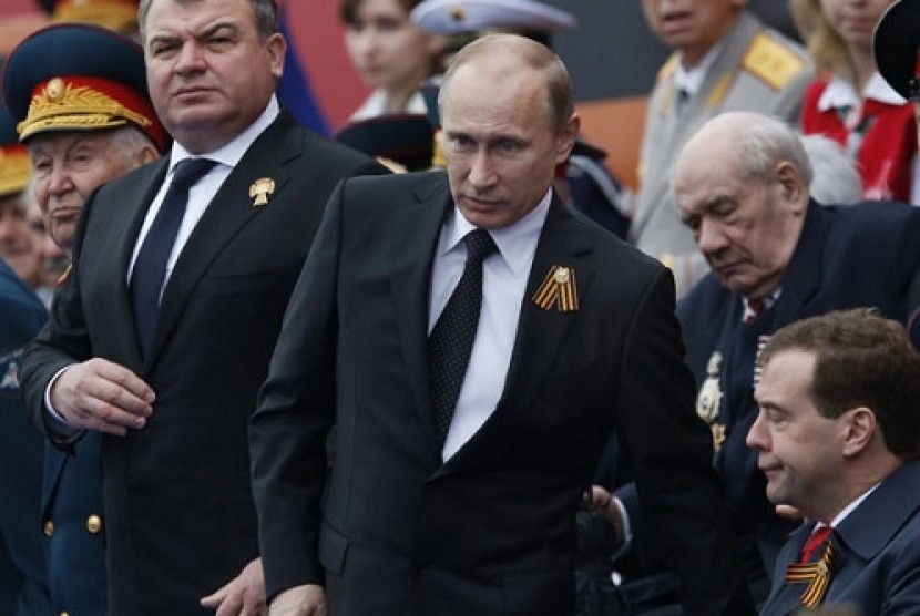 Russia's Defense Minister Anatoly Serdyukov, left, Russian President Vladimir Putin, center, and Prime Minister Dmitry Medvedev, bottom right, watch the Victory Day Parade, in Moscow. (file photo in March 2012)  