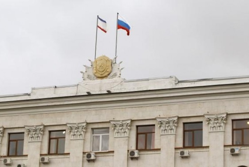 Russia's national flag (R) and Crimea's regional flag are seen on a building of Council of Ministers in Simferopol, March 5, 2014.