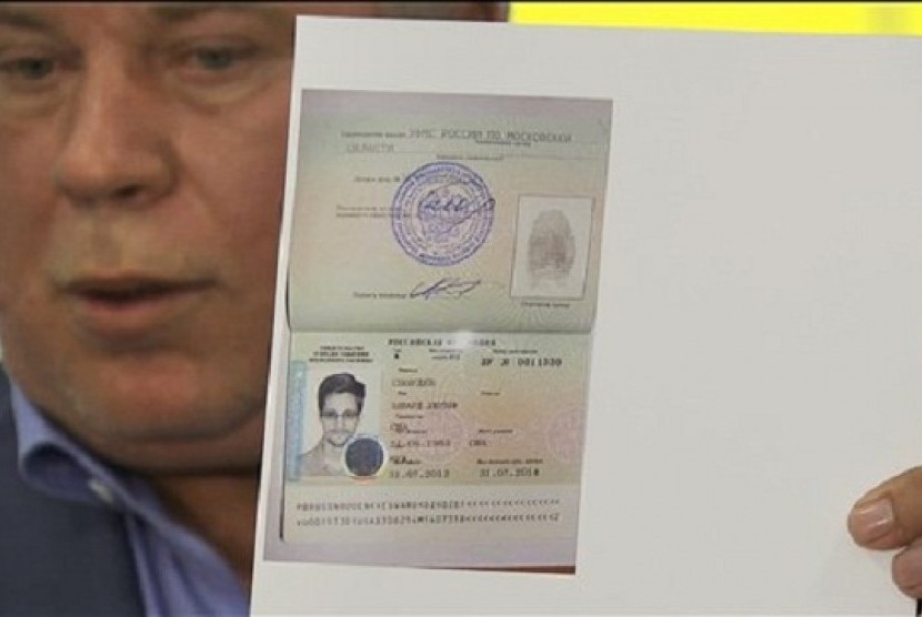 Russian lawyer Anatoly Kucherena shows a temporary document to allow Edward Snowden to cross the border into Russia while speaking to the media after visiting National Security Agency leaker Edward Snowden at Sheremetyevo airport outside Moscow, Russia, on