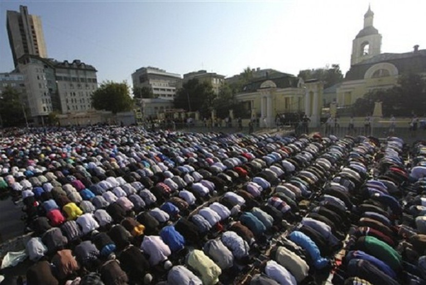 Russian Muslims pray outside a main Mosque which is under a reconstruction, not in the photo, in downtown Moscow on Thursday, Aug. 8, 2013. The Russian Orthodox church is at the background. 