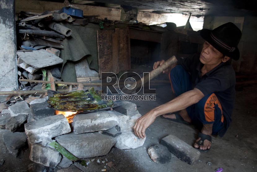 Saib (60) memasak menggunakan kayu bakar di rumahnya di kawasan Penjaringan, Jakarta Utara. (Republika/Rakhmawaty La'lang)
