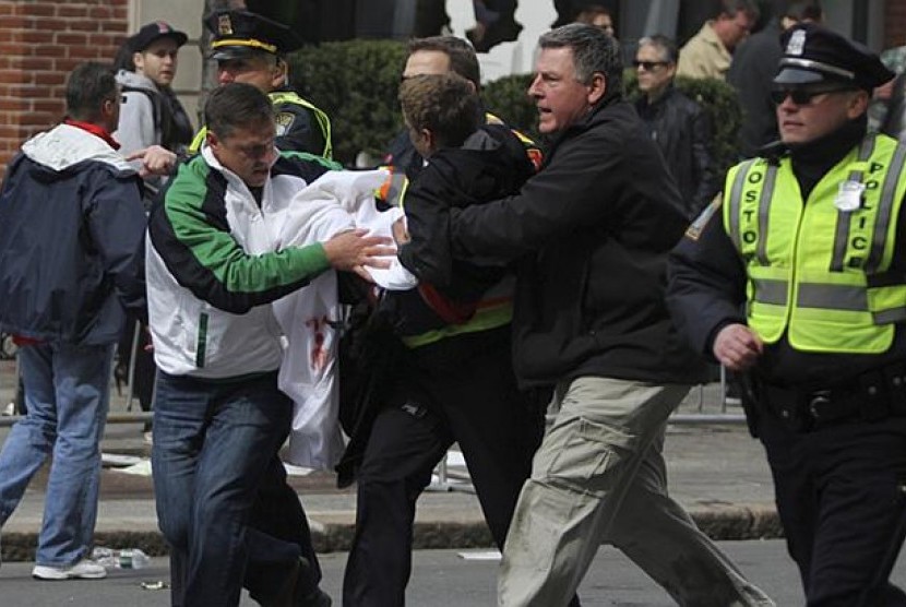 Salah satu korban dalam insiden ledakan bom pada Maraton Boston 2013, Senin (15/4/2013) dievakuasi oleh polisi dan petugas medis.