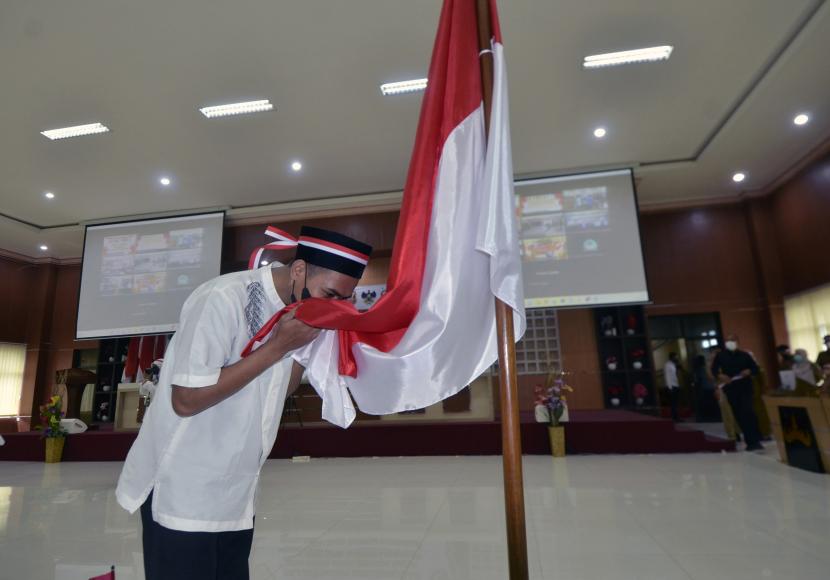 Salah satu mantan anggota Khilafatul Muslimin (KM) mencium bendera Merah Putih saat melakukan ikrar setia kepada NKRI dan Pancasila serta melepas baiat (janji taat) kepada Amir Khilafatul Muslimin di Kantor Wali Kota Bandar Lampung, Lampung, Senin (15/8/2022). Kegiatan yang diselenggarakan oleh Forum Komunikasi Pimpinan Daerah (Forkompimda) Lampung diikuti 51 mantan anggota dan simpatisan Khilafatul Muslimin (KM) dari berbagai daerah di Lampung. 