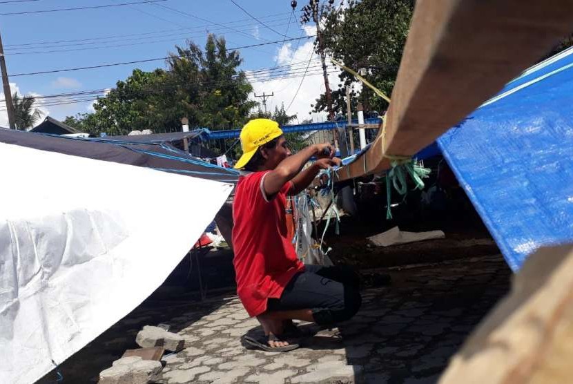 Salah satu pengungsi di Masjid Raya Baiturrahim, Palu, Sulawesi Tengah, Muhammad Nasir (34), tengah mereparasi tenda pengungsiannya, Ahad (14/10). 