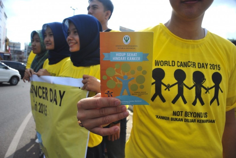 Salah satu peserta aksi menunjukkan selebaran sosialisasi tentang kanker pada aksi hari kanker sedunia.