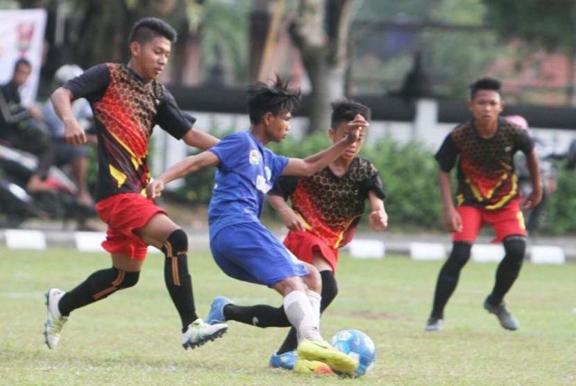Salah seoarng pemain Jawa Barat (biru) menggiring bola berusaha melewati pemain Kalimantan Barat pada laga Liga Sepak Bola Pelajar (LSP) Piala Menpora 2017 di Magelang, Jumat (8/9).