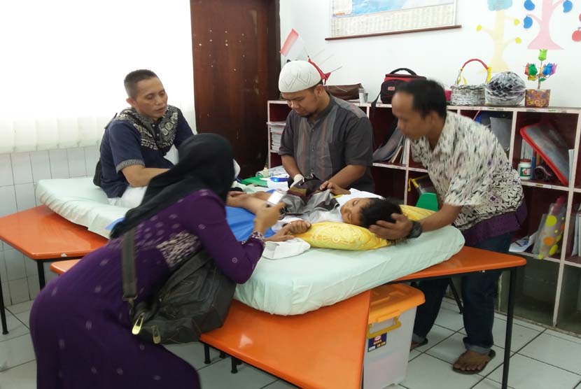 Salah seorang anak tengah dikhitan oleh dokter di SD Bina Insani Bogor,  Sabtu (24/10).