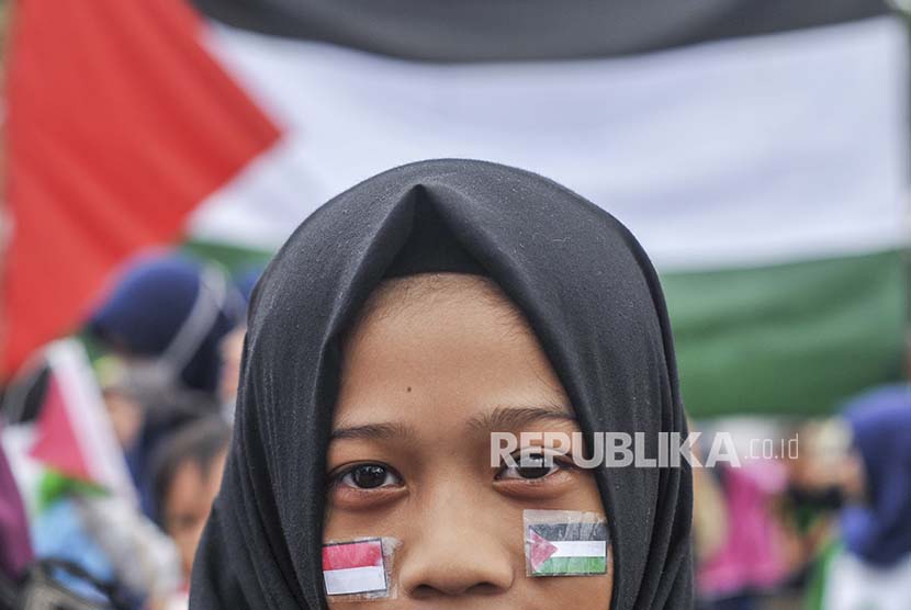 Salah seorang demonstran yang tergabung dalam Voice of Palestine Jawa Barat memasang bendera Indonesia dan Palestina di wajah.
