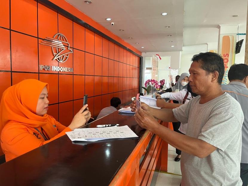 Salah seorang keluarga penerima manfaat (KPM) bansos dan sembako berkoordinasi dengan petugas Pos Indonesia, Sabtu (10/2)  di Jakarta.