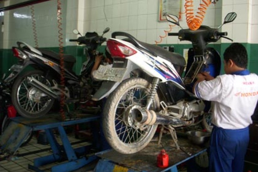 Salah seorang mekanik tengah memeriksa motor pelanggan.