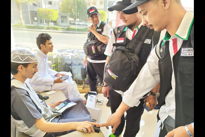 Salah seorang petugas provider di Arab Saudi (kiri) sedang meminta seorang petugas haji Daker Madinah, untuk menekan jari telunjuknya pada alat khusus untuk merekam sidik jari, pada Jumat (5/7), Makkah, Arab Saudi. 