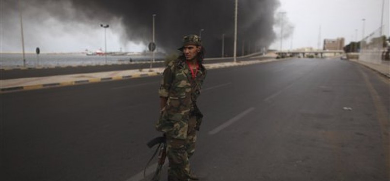 Salah seorang prajurit NTC berdiri di tengah jalan ketika gudang senjata milik pasukan Qadafi meledak di kawasan pelabuhan Tripoli, Libya, Sabtu (24/9).