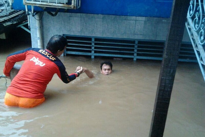 Salah seorang relawan tengah mengevakuasi korban banjir