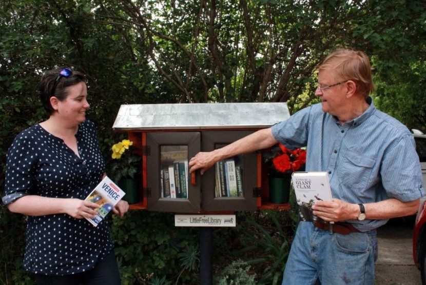 Sarah dan John memeriksa buku di Perpustakaan Mini Gratis miliknya. 