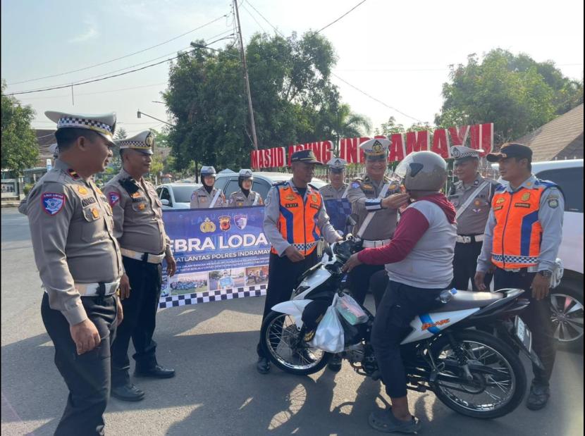 Satlantas Polres Indramayu bagikan helm gratis kepada pengendara sepeda motor, saat menggelar Operasi Zebra Lodaya 2024, di Titik 0 KM Kecamatan/Kabupaten Indramayu, Jumat (25/10/2024). 