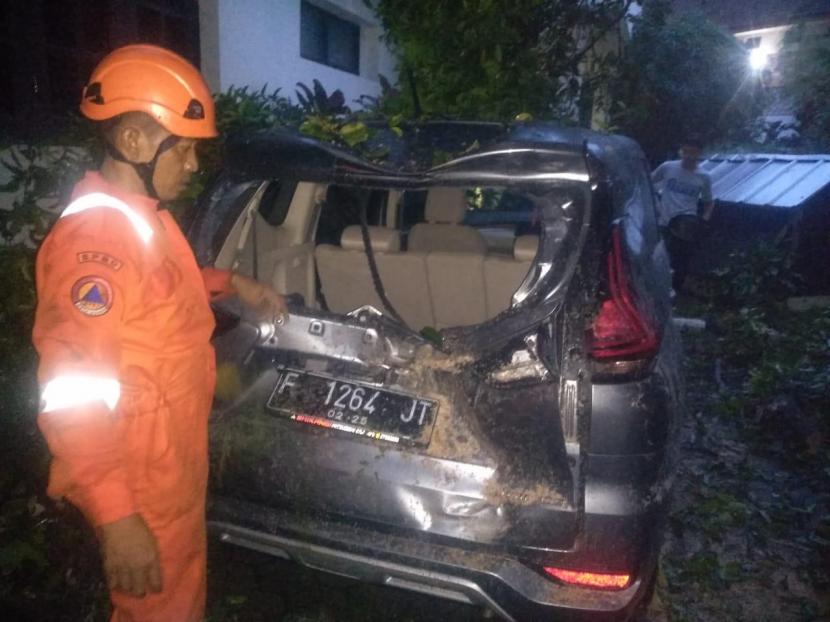Satu unit mobil di Jalan Jalak Harupat, Kelurahan Babakan, Kecamatan Bogor Tengah, Kota Bogor rusak tertimpa pohon jenis tanjung yang tumbang pasca hujan deras dan angin kencang, Selasa (10/11) sore. 