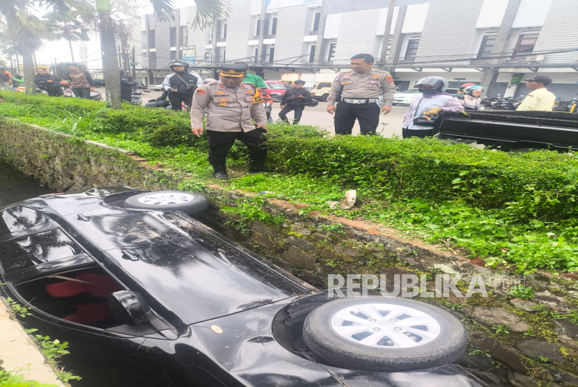 Satu unit mobil Grand Livina nyungsep alias jatuh ke selokan di Kompleks Perumahan Batununggal Indah, Kota Bandung, Selasa (28/1/2025)