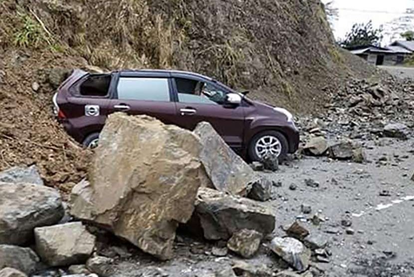 Satu unit mobil tertimbun material longsoran tanah dan batu di kawasan Kebun Kopi, kota Palu di Sulawesi Tengah, Sabtu (29/9).