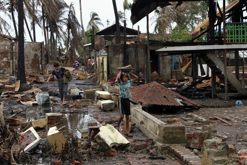 Saturday, June 16, 2012 file photo, a girl and a woman carry useable bricks from damaged buildings in Sittwe, capital of Rakhine state in western Myanmar. Communal violence is grinding on in western Myanmar six weeks after the government declared a state o