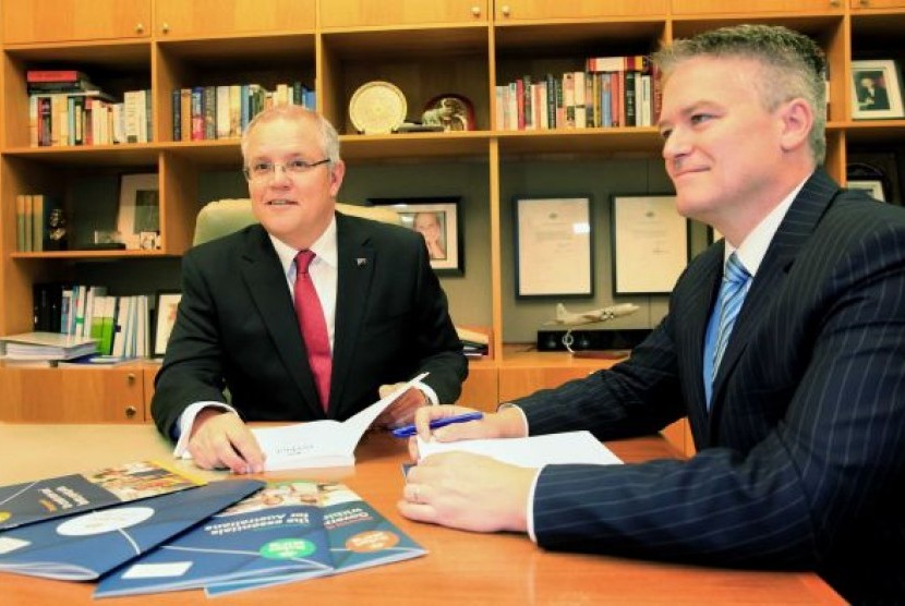 Scott Morrison (kiri) dan Mathias Cormann (kanan) memeriksa dokumen anggaran di Canberra, Australia..