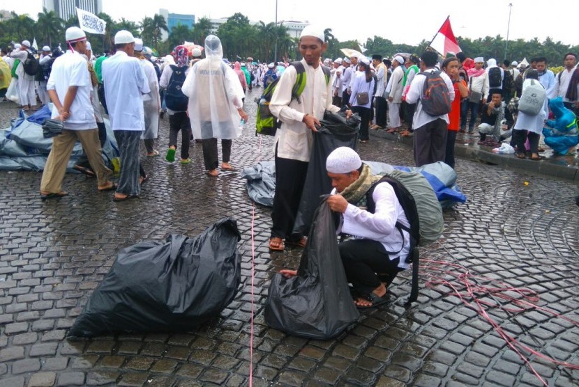 Sebagian massa melakukan pengumpulan sampah secara sukarela di Lapangan Monas, Jakarta usai melaksanakan shalat Jumat bersama, Jumat (2/12).