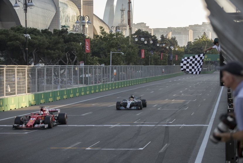 Sebastian Vettel melintasi garis finis GP Azerbaijan di depan Lewis Hamilton, pada Ahad (25/6).