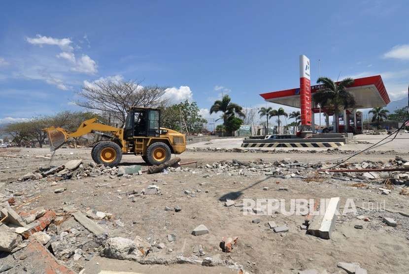 Sebuah alat berat membersihkan material sisa gempa dan tsunami yang menutupi badan jalan di Palu, Sulawesi Tengah, Jumat (5/10). 