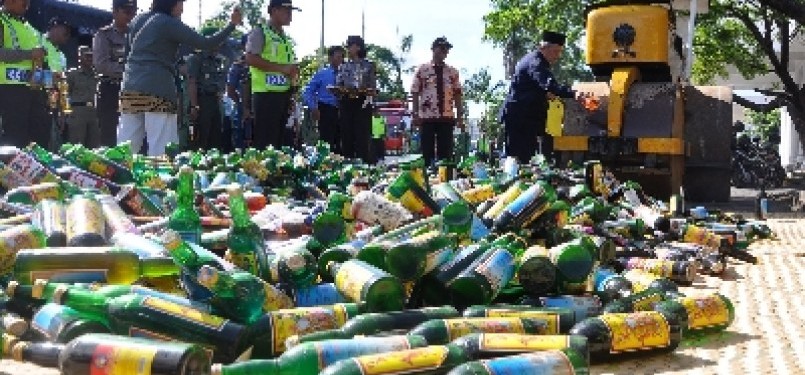 Sebuah alat berat memusnahkan ribuan botol minuman keras (miras). 