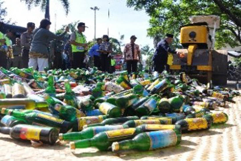 Sebuah alat berat memusnahkan ribuan botol minuman keras (miras). 