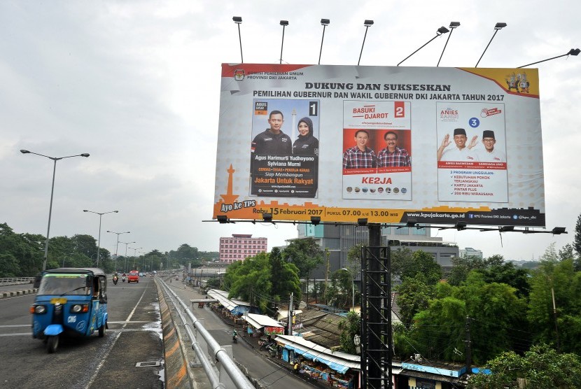 Sebuah angkutan umum melintas di dekat baliho sosialisasi Pilkada Gubernur dan Wakil Gubernur DKI Jakarta Tahun 2017 di Jakarta, Jumat (10/2).